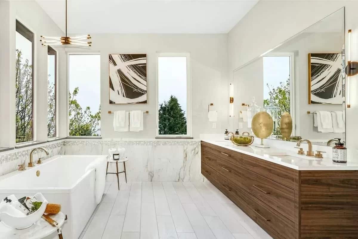 Primary bathroom with a dual sink vanity and a soaking tub over the wide plank flooring.