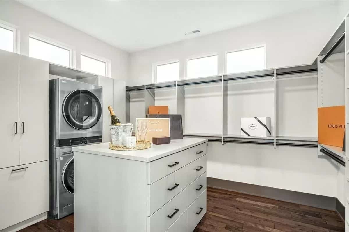 Primary walk-in closet with clerestory windows, stackable washer and dryer, and a center island.