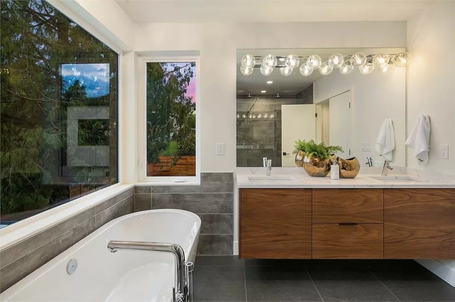 Primary bathroom with a floating vanity and a soaking tub under the picture windows.