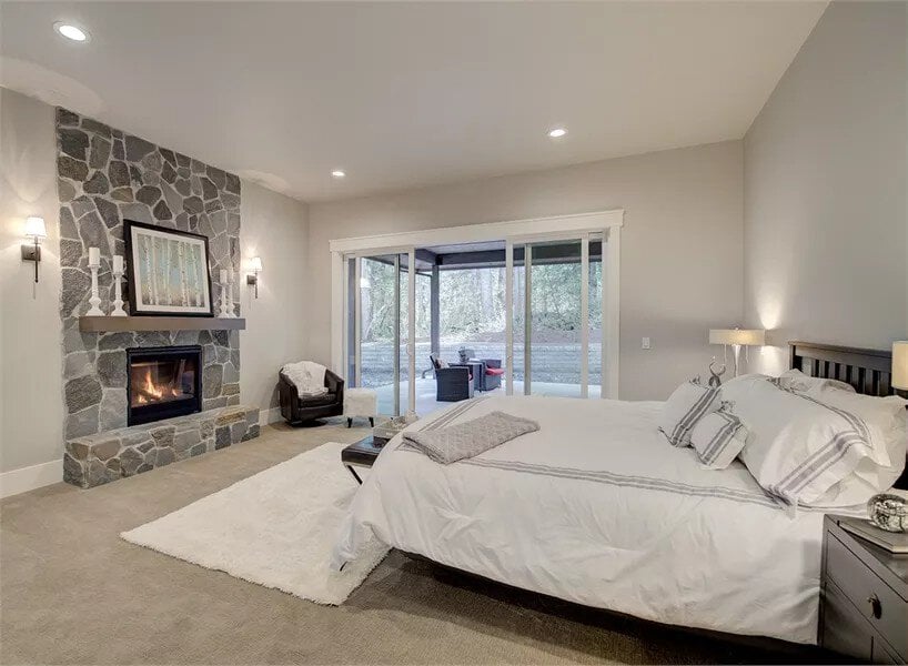 Primary bedroom with a stone fireplace and a private patio accessible through sliding glass doors.