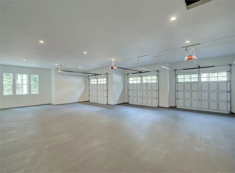 Garage with concrete flooring and three large paneled doors.