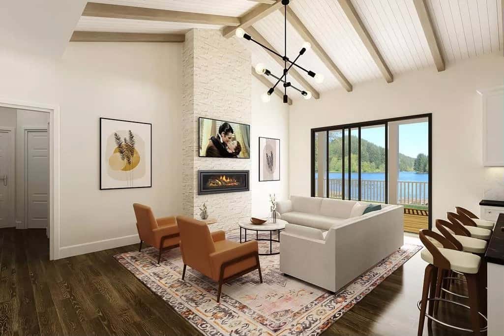 Great room with an L-shaped sofa, brown armchairs, and a fireplace under a vaulted ceiling with exposed beams.