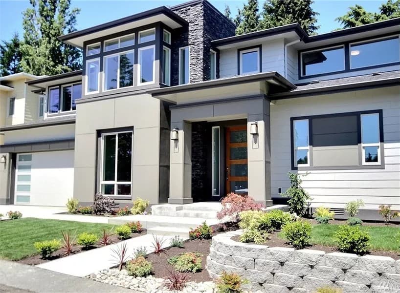 Front view of the house with a covered entry, a 4-car tandem garage, and a multitude of windows.