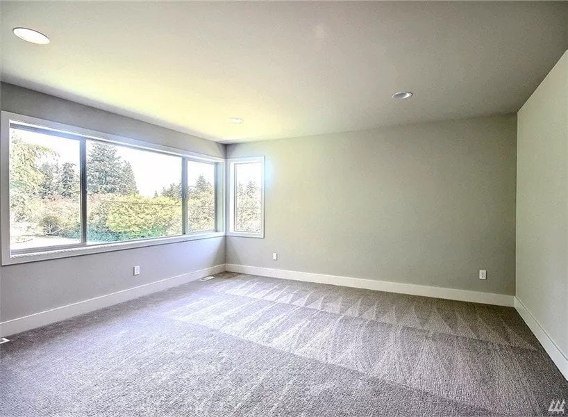 Primary bedroom with a carpeted floor and a panoramic window flooding the room with natural light.