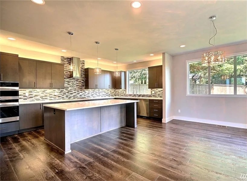 Kitchen and dining area illuminated by recessed ceiling lights and sliding windows.