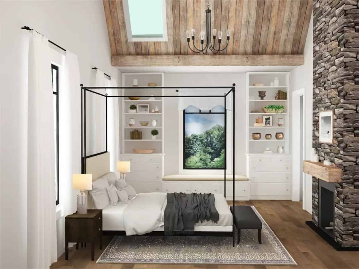 Primary bedroom with a canopy bed, a stone fireplace, a window seat, and a vaulted ceiling fitted with a skylight. 