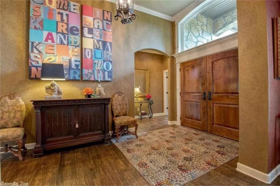 Foyer with double front doors and a wooden console table flanked by traditional chairs.