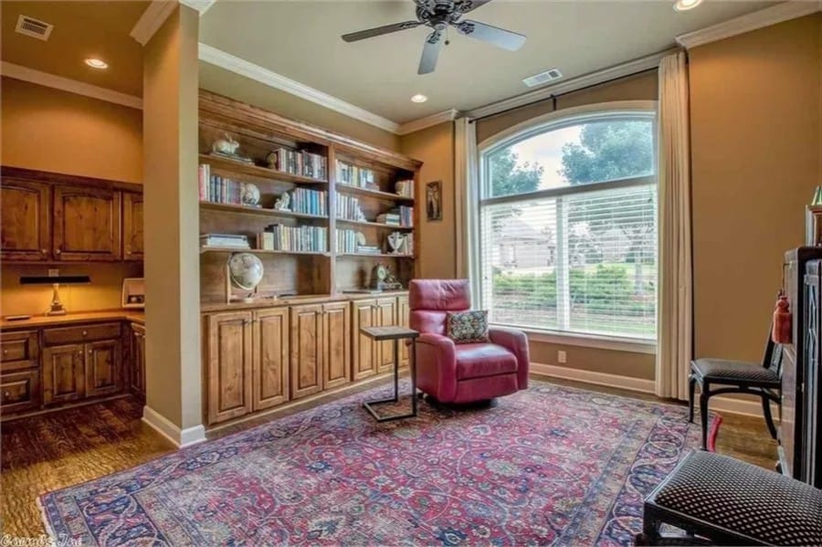 Study with built-in bookshelves and a vintage area rug that lays on the hardwood flooring.