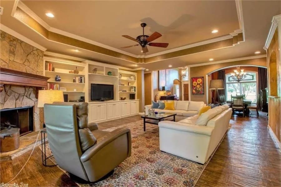 Family room with leather seats, a corner fireplace, and a TV under a tray ceiling.