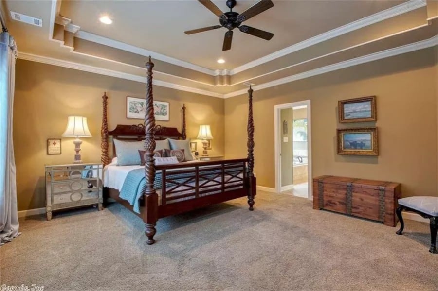 Primary bedroom with a tray ceiling, a four-poster bed, and an ensuite bathroom.