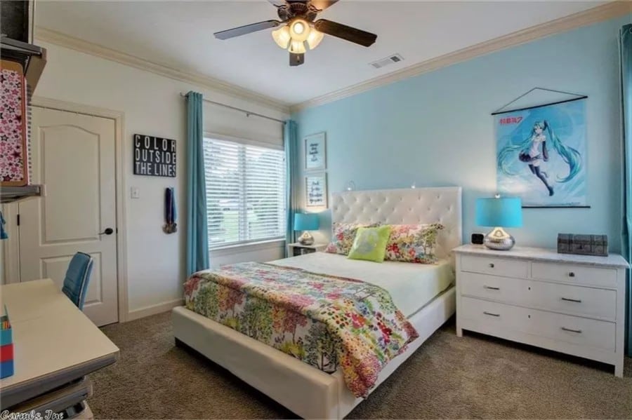 Bedroom with white cabinets and a matching tufted bed against the blue accent wall.