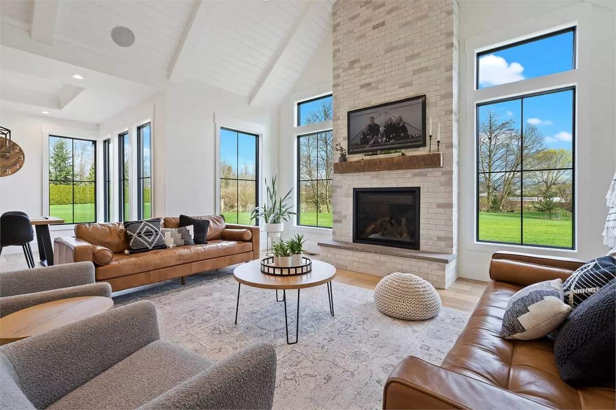 Great room with leather sofas, gray chairs, and a brick fireplace.