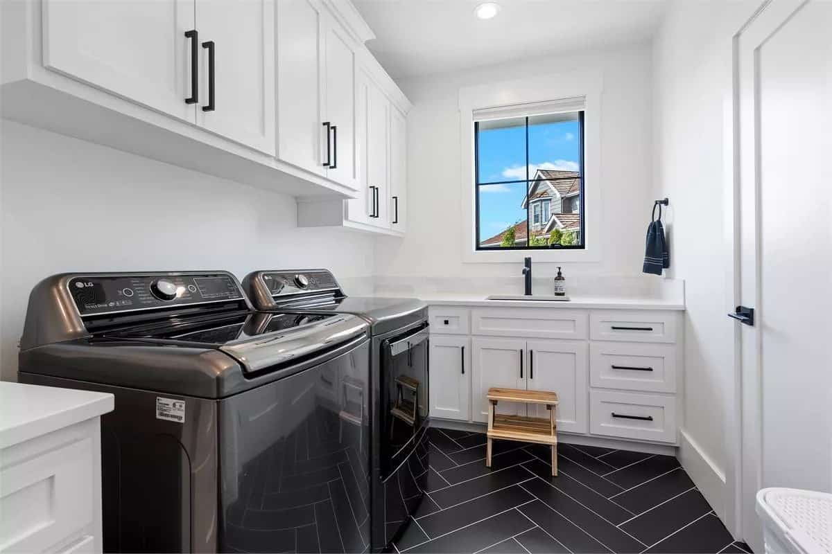Laundry room with white cabinets, contrasting appliances, and a utility sink.