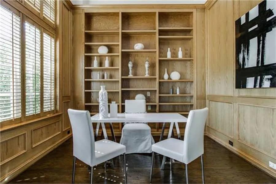 Office with wooden built-ins and a white desk complemented with matching chairs.