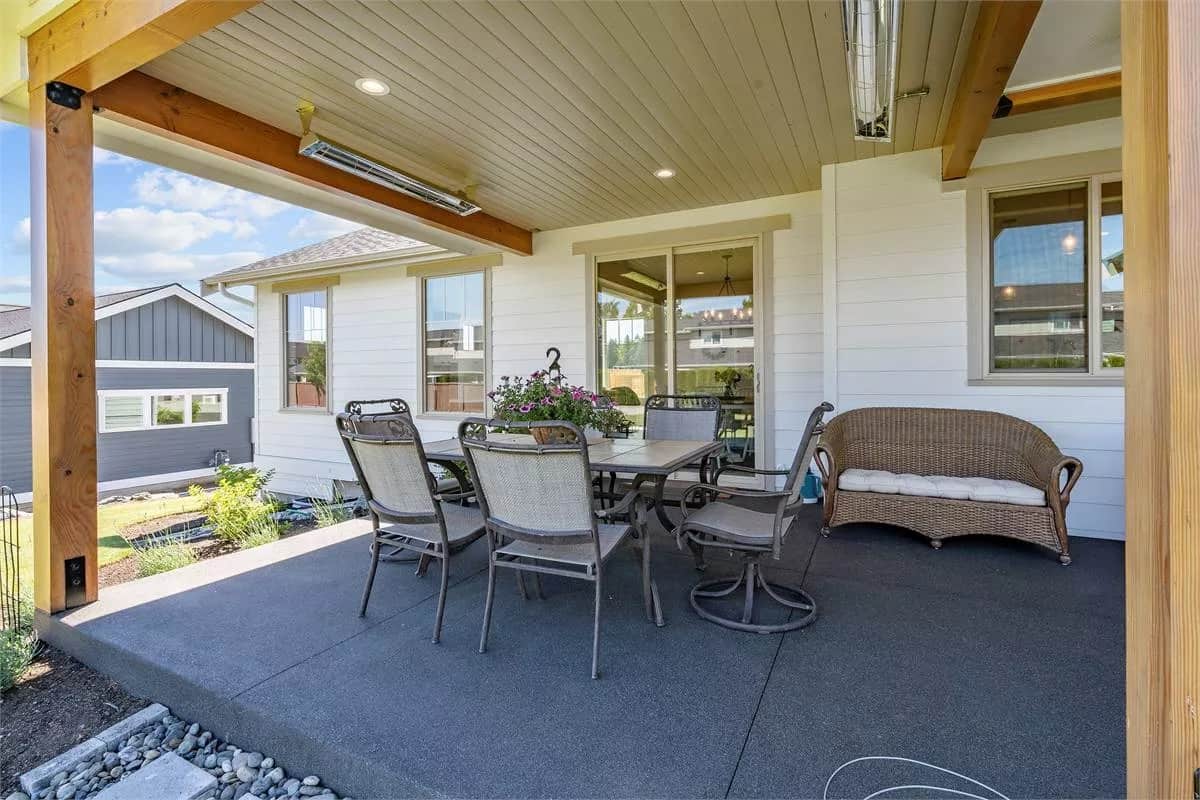 Covered patio with a wicker sofa and a metal dining set over the concrete flooring.