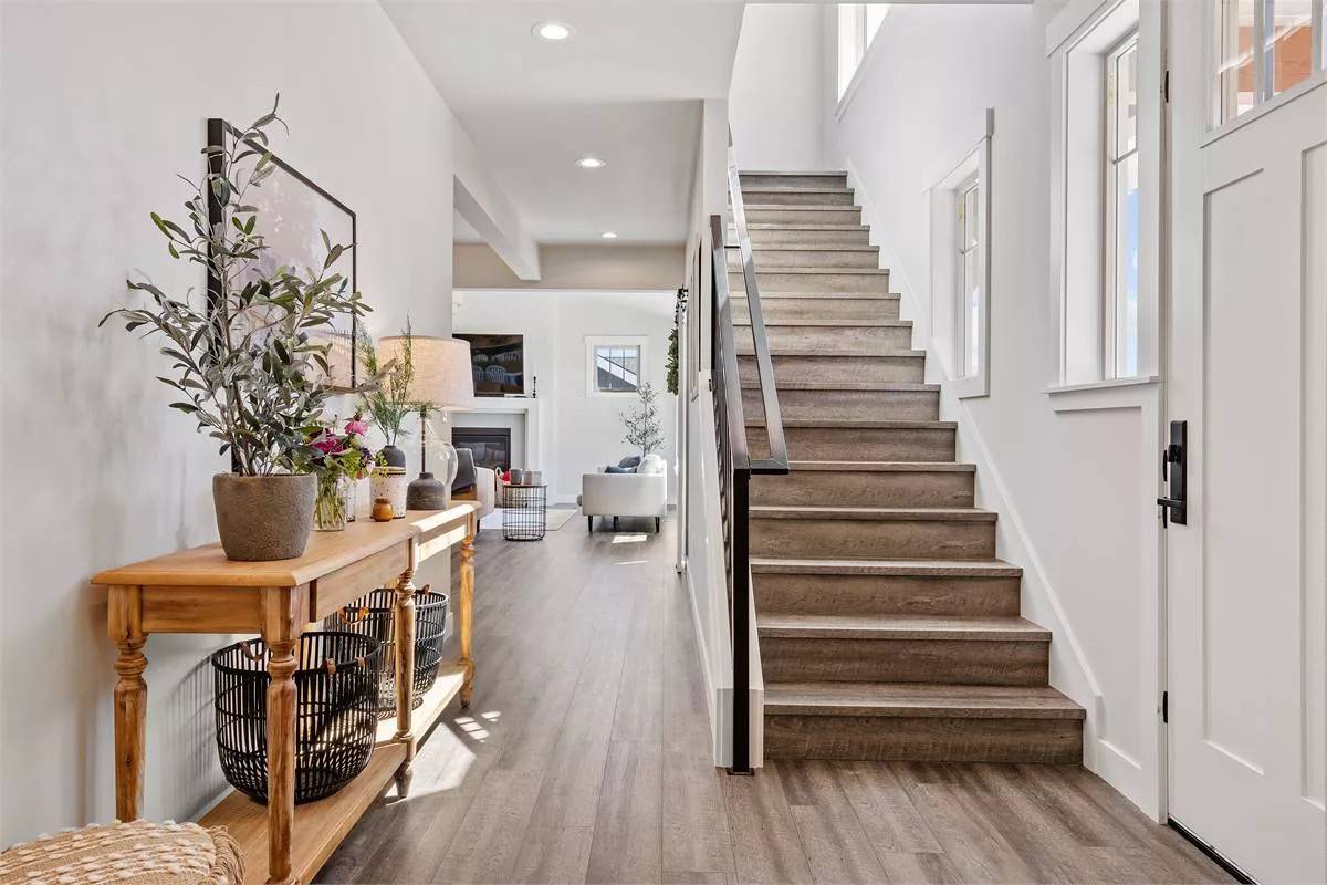 Foyer with a wooden console table and a staircase that blends in with the hardwood floor.