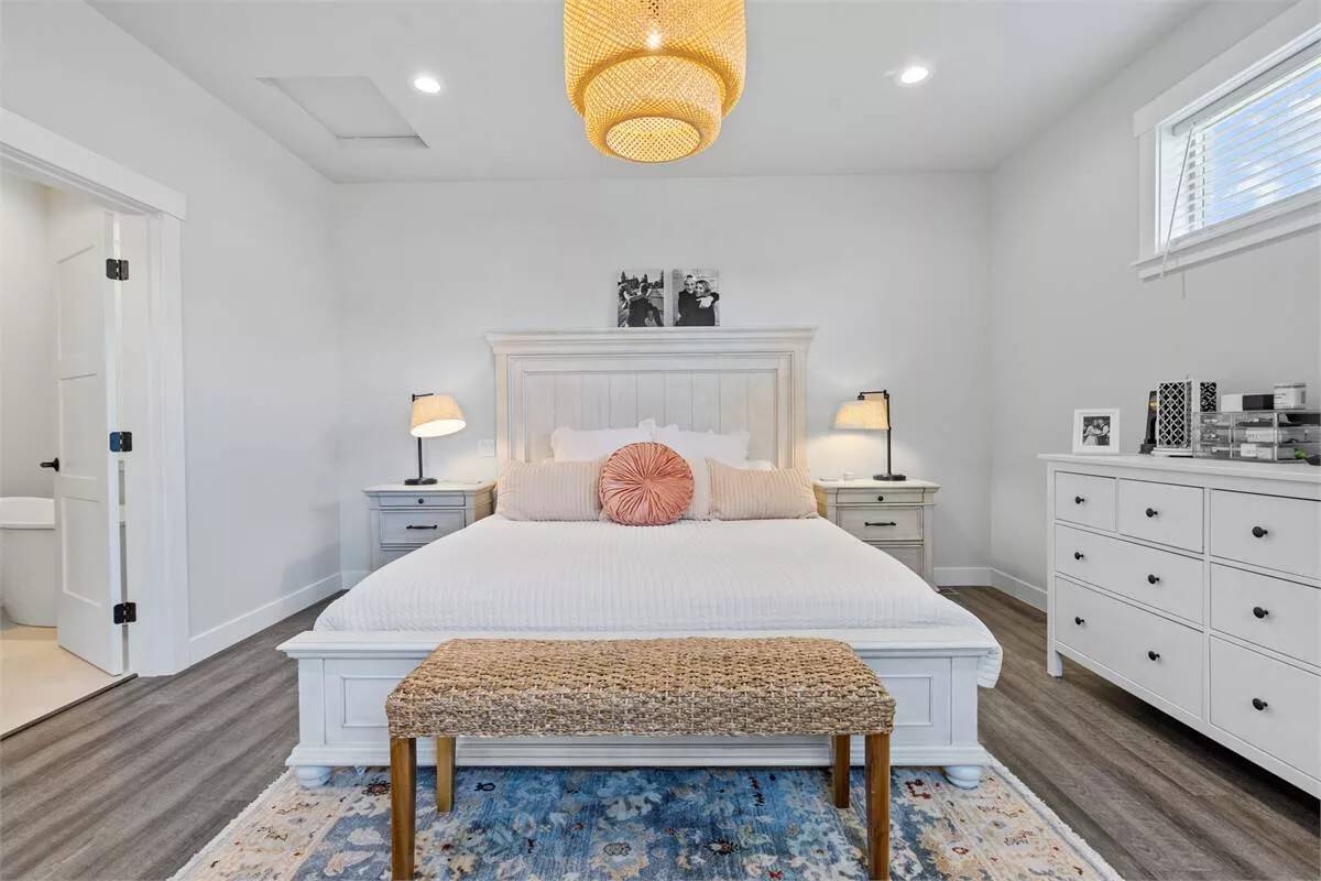 Primary bedroom with a white dresser and a beadboard bed complemented with a wicker bench.