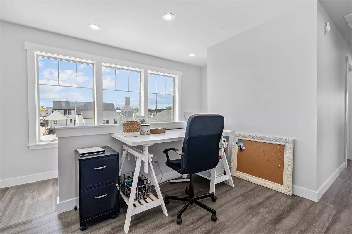 Study with a white desk and a trio of windows bringing natural light in.