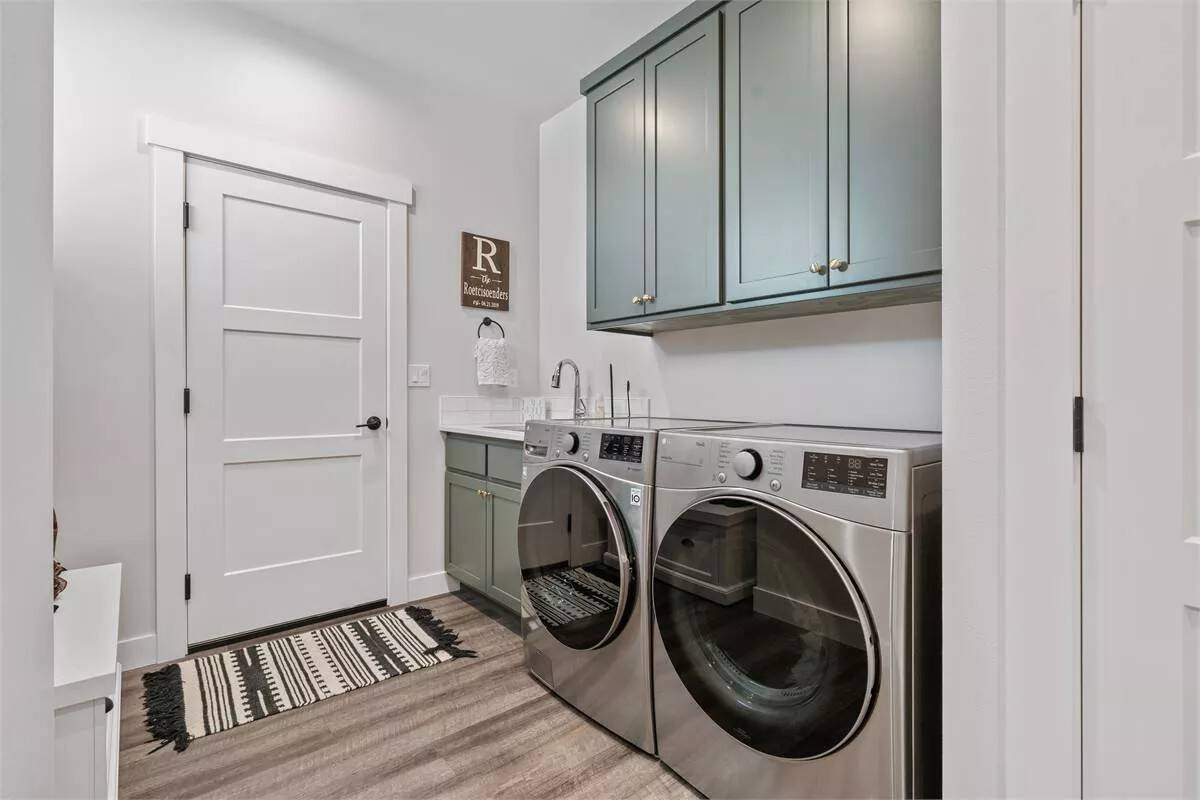 Laundry room with sage green cabinets and a utility sink.