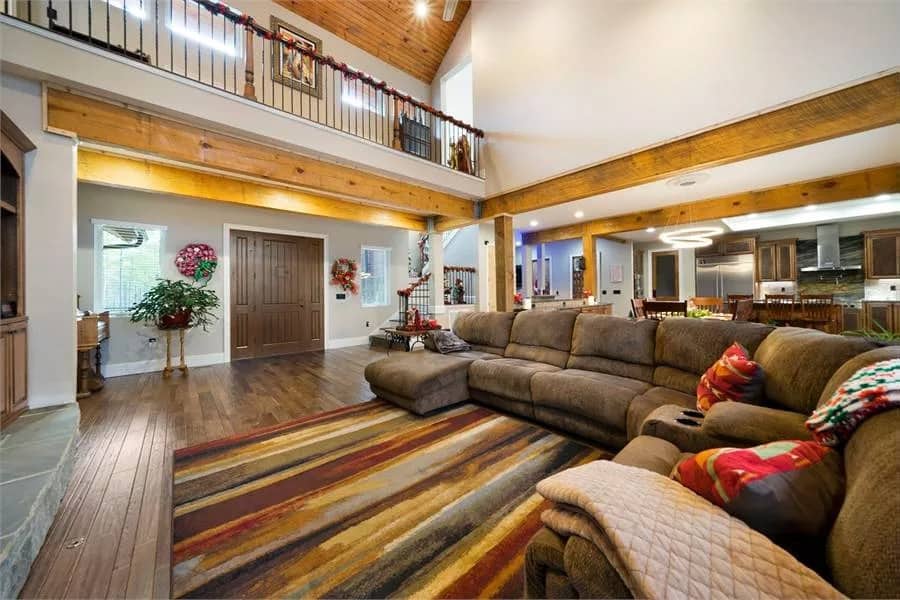 The great room includes a striped area rug and a view of the second-level balcony.
