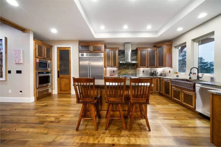 Kitchen with a farmhouse sink, wooden cabinets, and a matching island that blends in with the hardwood floor.