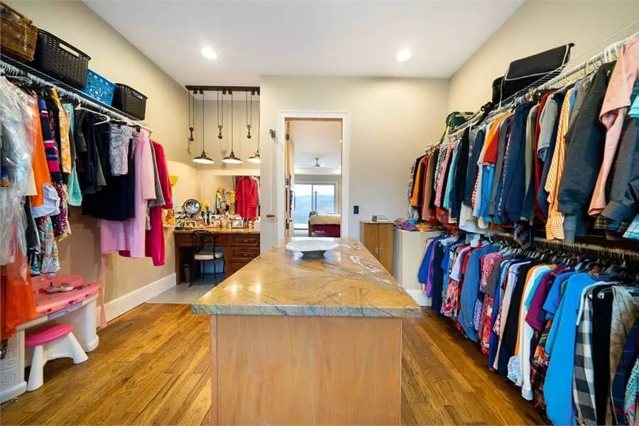 Primary walk-in closet with ample storage, a vanity, and a center island.