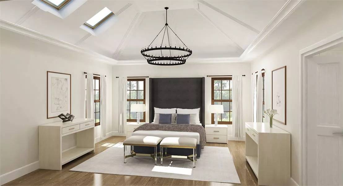 Primary bedroom with a custom bed, cushioned footstools, and a vaulted ceiling fitted with skylights.
