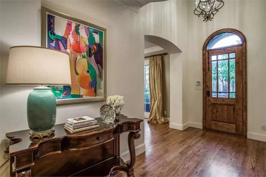 Foyer with a glazed entry door and a wooden console table adorned with an abstract painting.