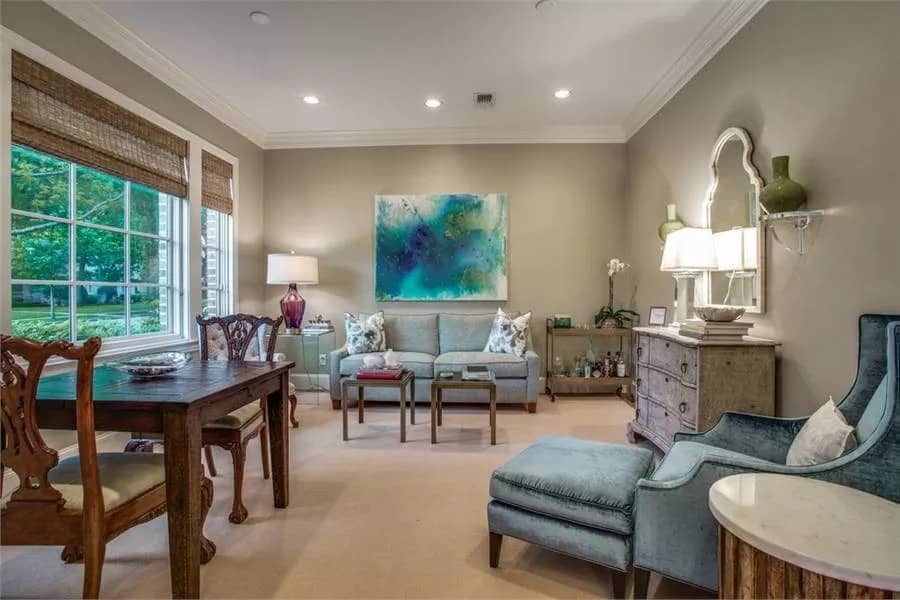 Living room with blue velvet seats and a wooden dining set over the carpeted floor.