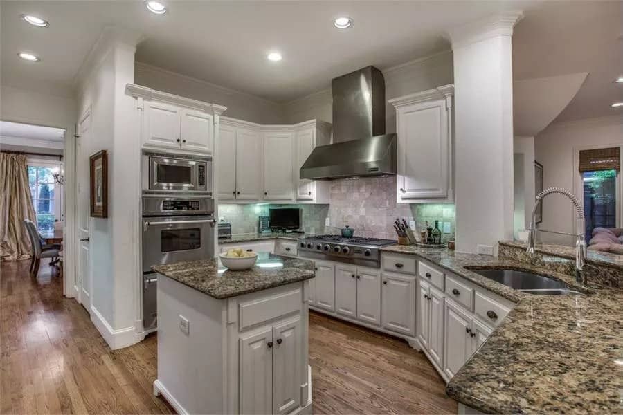 Kitchen with white cabinets, granite countertops, and a small center island.