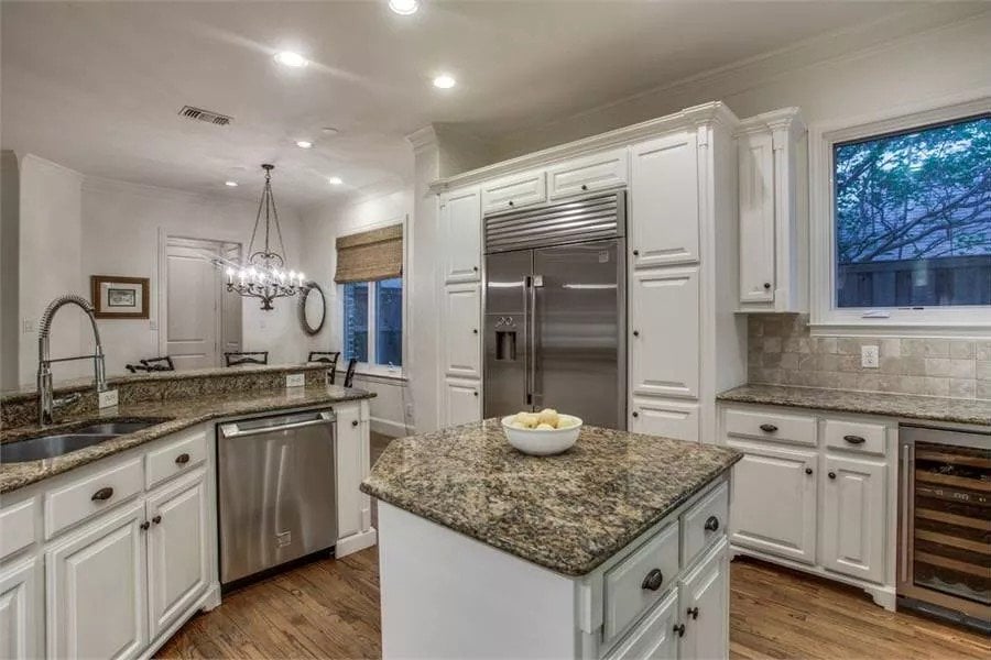 The kitchen includes stainless steel appliances and a peninsula with double sink and a raised eating bar.