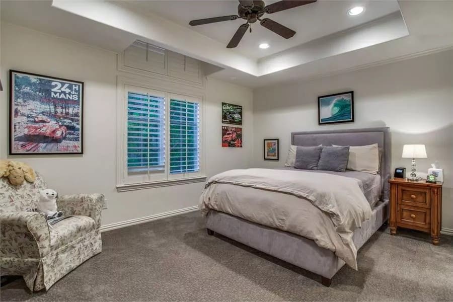 Bedroom with a tray ceiling, an upholstered bed, and a skirted chair.