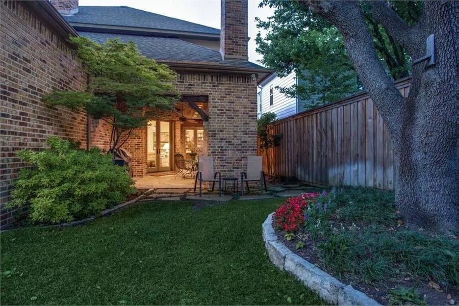 Backyard with a lush green lawn and outdoor fireplace.