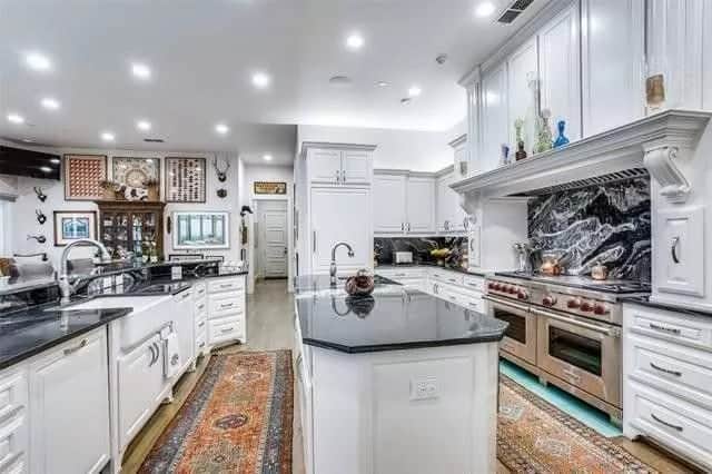Kitchen with white cabinets, stainless steel appliances, a farmhouse sink, and a center island.