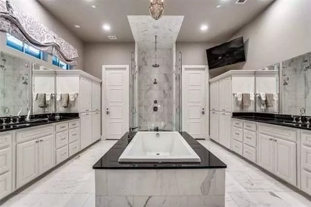 Primary bathroom with his and her vanities, a soaking tub, and a tiled shower.
