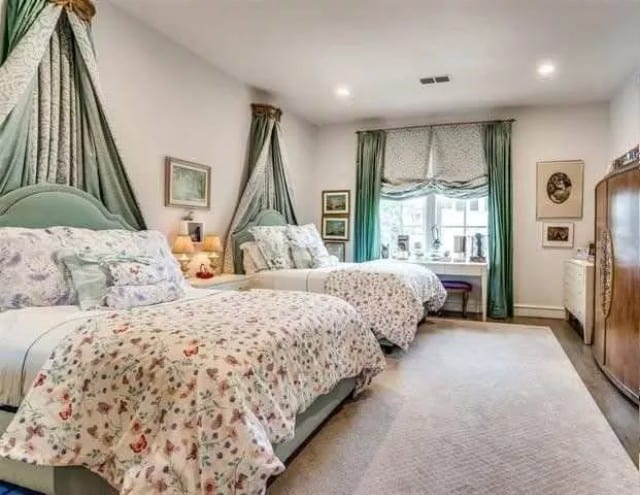 Secondary bedroom with two beds and a white desk by the window.