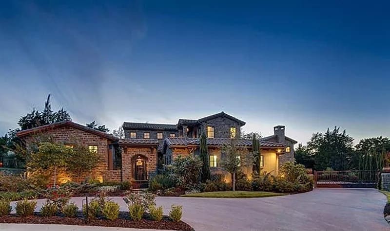 Front view of the house with clay tiled roofs, brick cladding, and a covered entry.