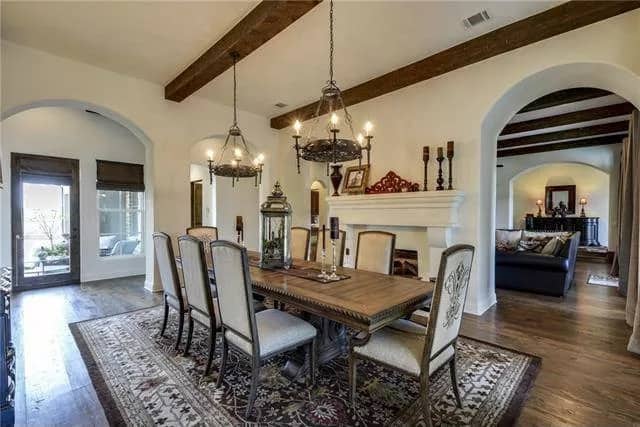 Dining room with an 8-seater dining set, a double-sided fireplace, and a beamed ceiling.