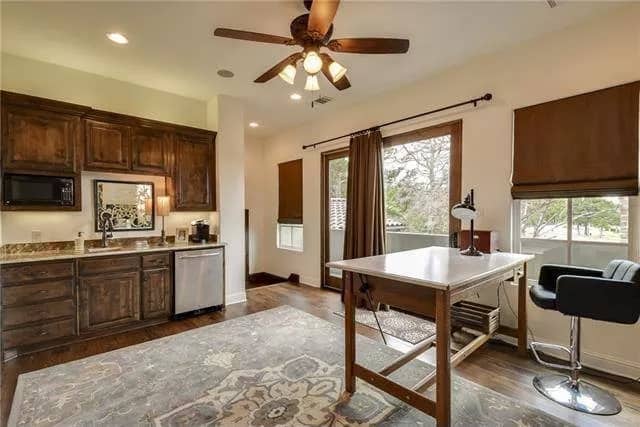 Office with a wooden desk, a leather stool, and a wet bar.