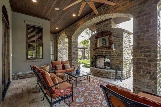 Lanai with cushioned sofas, a matching coffee table, and a stone fireplace.