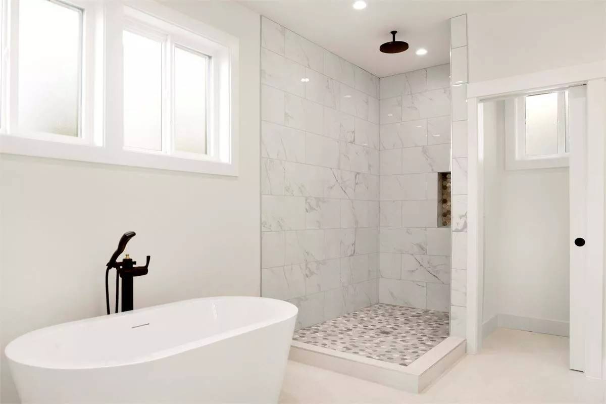 Primary bathroom with a tiled shower and a soaking tub under the sliding windows.