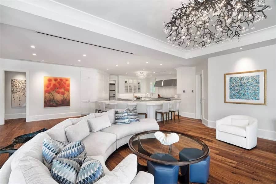 Family room with a curved sectional sofa, a round-back chair, and a glass-top coffee table complemented with hexagonal stools.