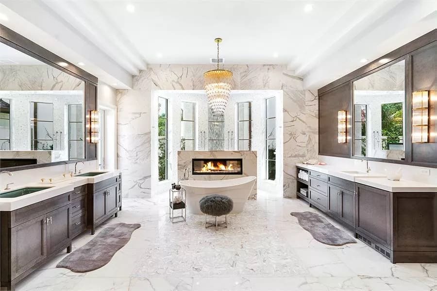 Primary bathroom with his and her vanities, a walk-through shower, and a soaking tub warmed by a fireplace.