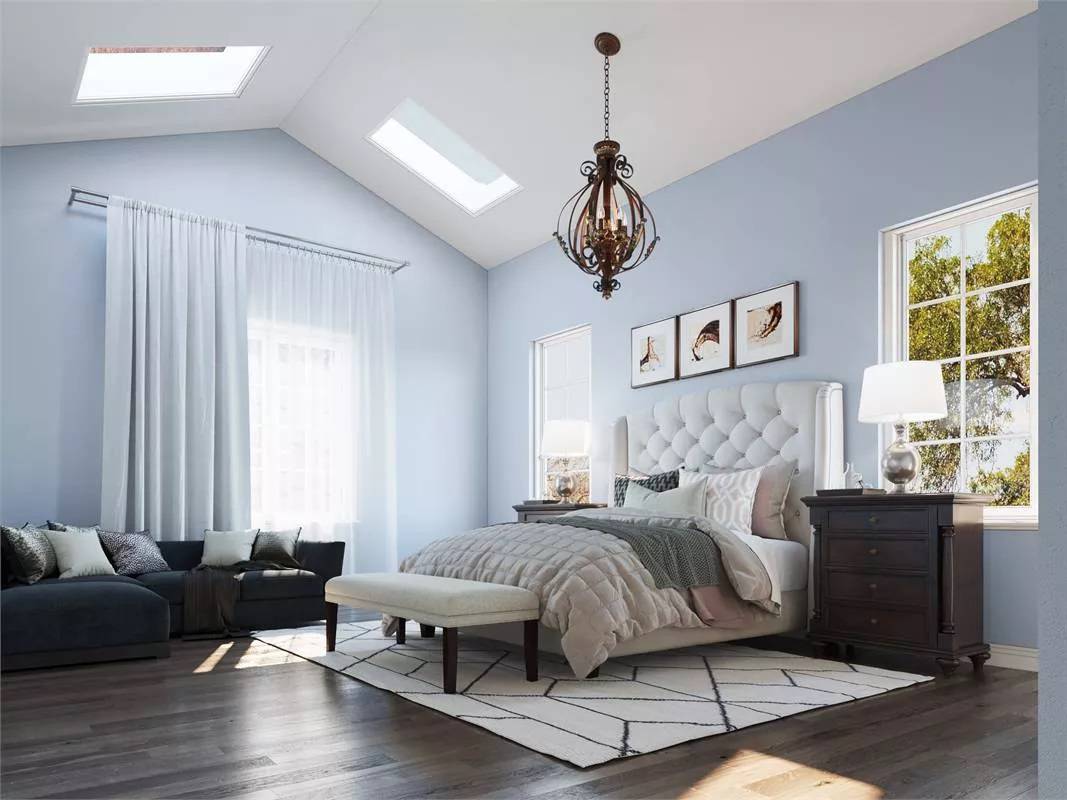 Primary bedroom with a tufted bed, an L-shaped sofa, and a cathedral ceiling fitted with skylights.