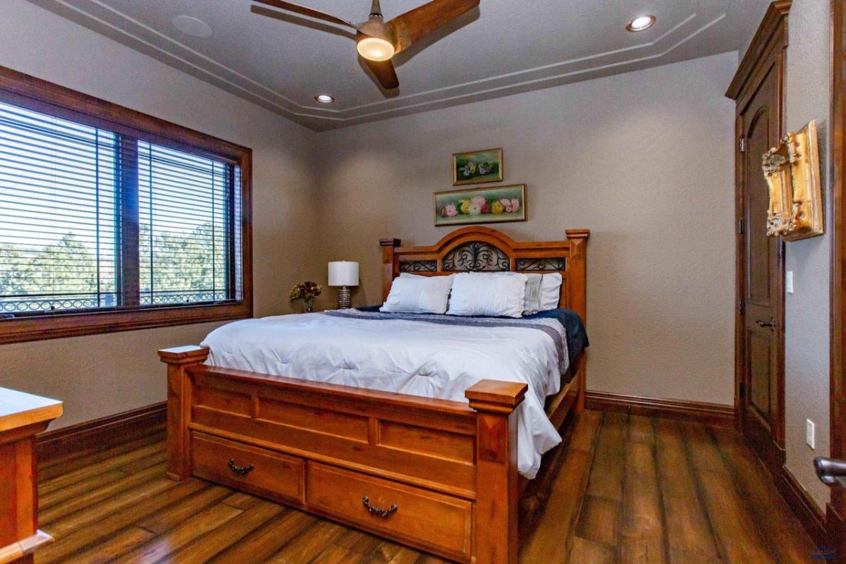 Bedroom with a large bed, wood flooring and glass windows.