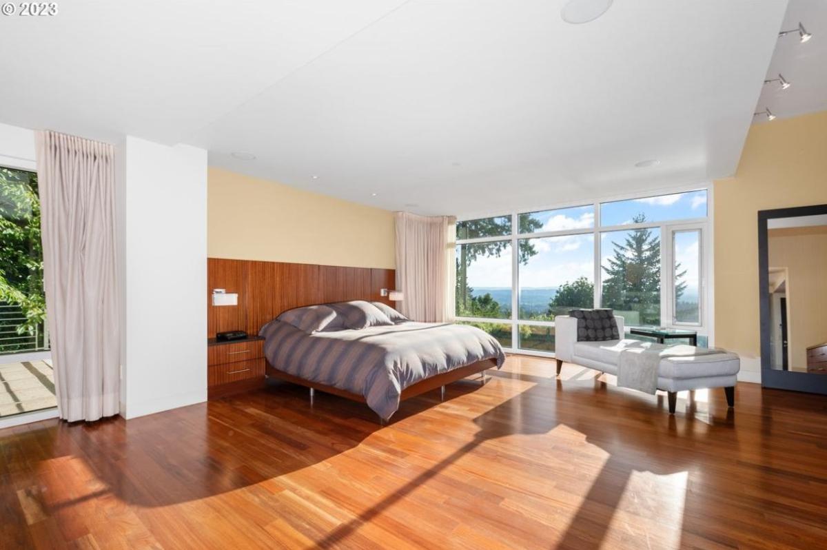 Bedroom with a large bed, wood flooring and glass doors.