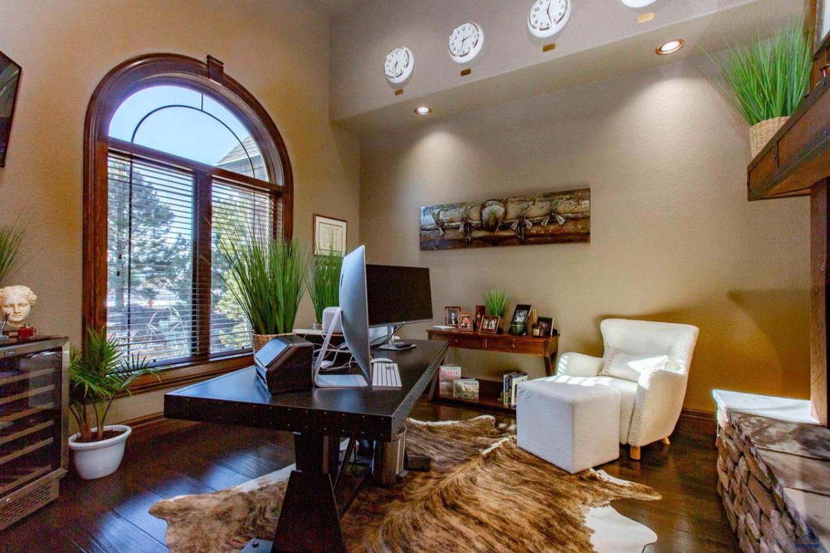 Home office with a large desk, computers and wood flooring.