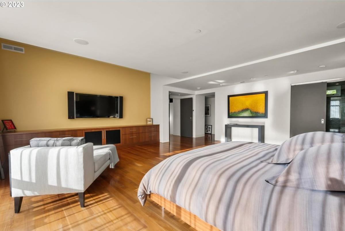 Bedroom with a large bed, wood flooring and a TV.
