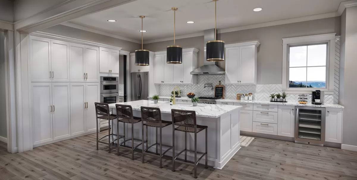 Kitchen with white cabinetry, high-end appliances, and a breakfast island with seating for four.