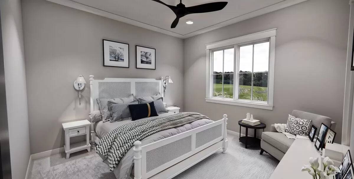 Primary bedroom with a white bed and cushioned armchair over the carpeted floor.